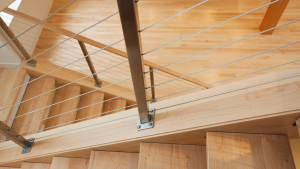 Modern wood staircase with stainless steel cable balusters and light maple treads.
