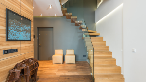 Modern open staircase with wooden treads and glass railings in a minimalist home interior.
