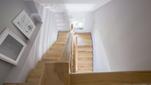 U-shaped wooden staircase with natural light and minimalist decor in a modern multi-story home.