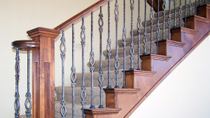 Traditional staircase with wooden handrails and decorative wrought iron balusters.
