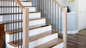 Contemporary staircase with light wood railings, black balusters, and contrasting wood treads.