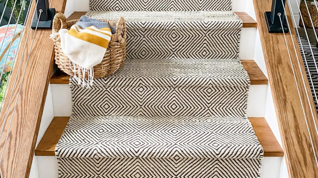 Staircase with a bold black-and-white patterned runner and wooden handrails.