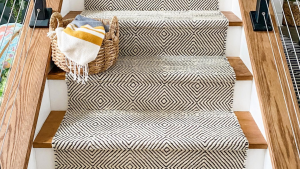 Staircase with a bold black-and-white patterned runner and wooden handrails.