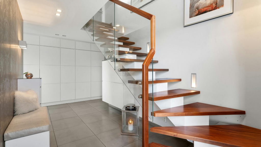 Modern wooden staircase with glass railing in a contemporary home interior.