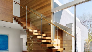 Modern staircase with glass balusters and a floating wooden handrail.