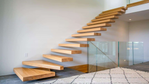 Modern floating staircase with wooden treads and glass railings in an open-concept living space.