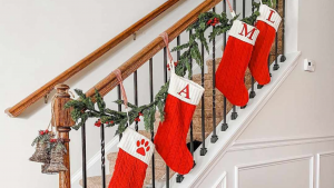 Christmas stockings hanging along a decorated staircase with greenery and festive accents, creating a warm and inviting holiday atmosphere.
