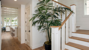 Light wood handrail in a bright coastal-style home with white stair balusters and natural wood flooring.