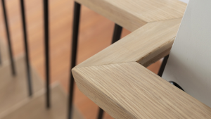 Close-up of a square wooden handrail with clean, modern lines and black metal balusters.