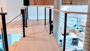 Coastal staircase style featuring light wood treads and cable railing in a bright, airy home