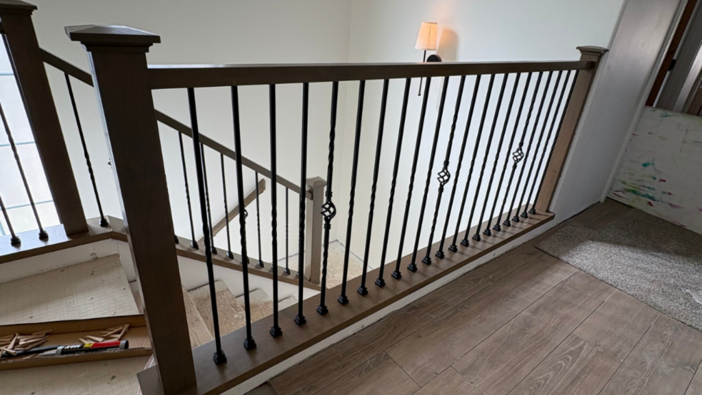 Traditional staircase with dark wood handrail and newel posts paired with black metal balusters on an upper landing