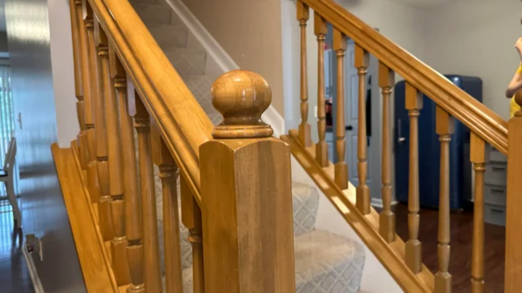 Outdated staircase with golden oak wood stain, traditional turned balusters, and carpeted stair treads in a residential home