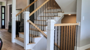 Modern farmhouse staircase renovation featuring natural white oak treads, white-painted risers and square newel posts, with black metal balusters creating a bright and airy California-inspired interior.