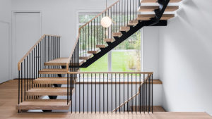 Modern metal staircase illuminated by bright natural light from large windows.