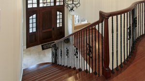 Dark rich wood staircase, flooring, and railing contrasting with white walls in a bright home interior.
