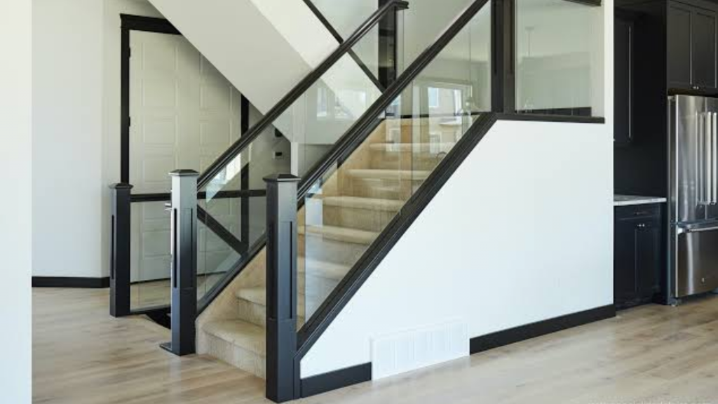 Modern staircase with tempered glass railings, black metal frame, and light-colored stairs in a contemporary home.